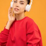 Trends - Woman in Red Sweatshirt and Blue Jeans Wearing White Headphones