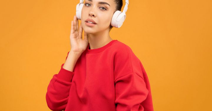 Trends - Woman in Red Sweatshirt and Blue Jeans Wearing White Headphones