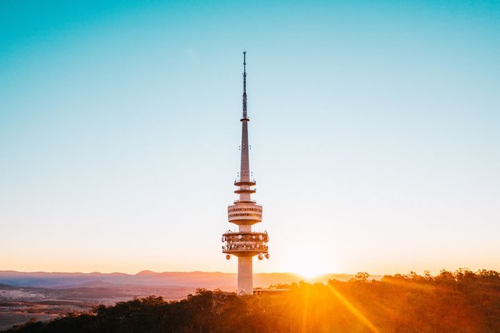 5g - the sun is setting behind a tower on top of a hill